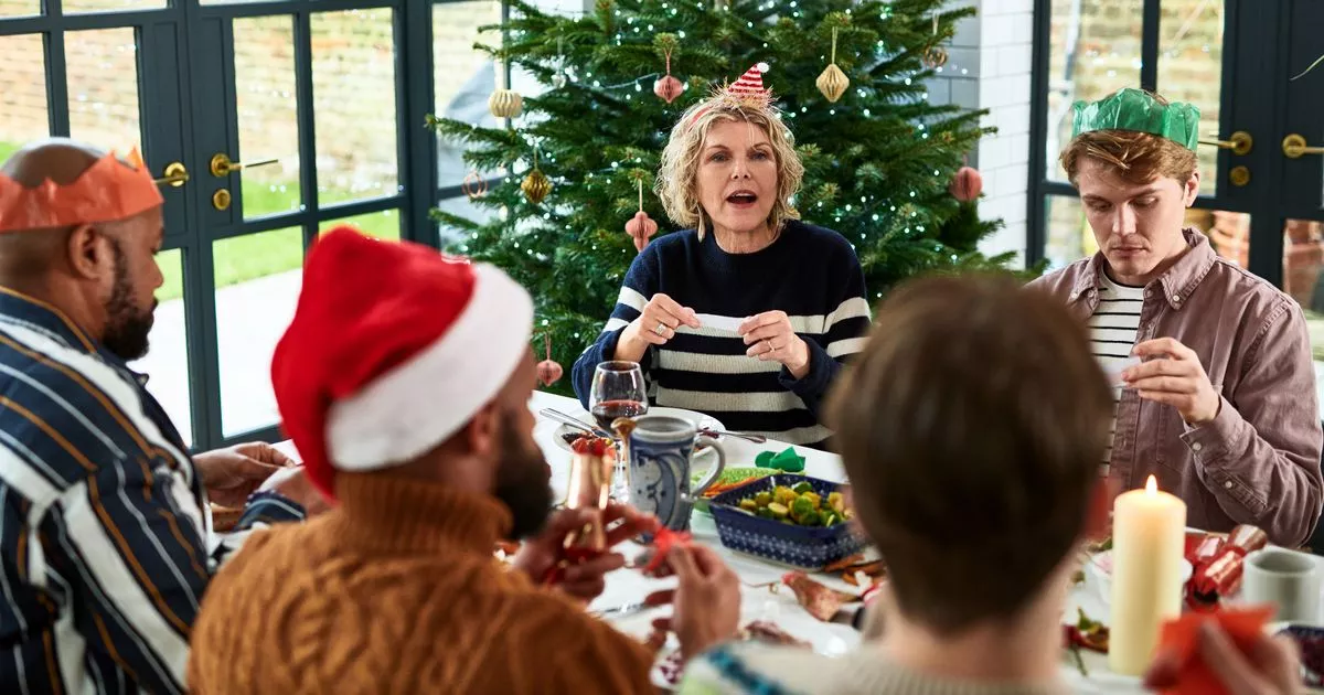 3 Family telling jokes from Christmas crackers at dinner table